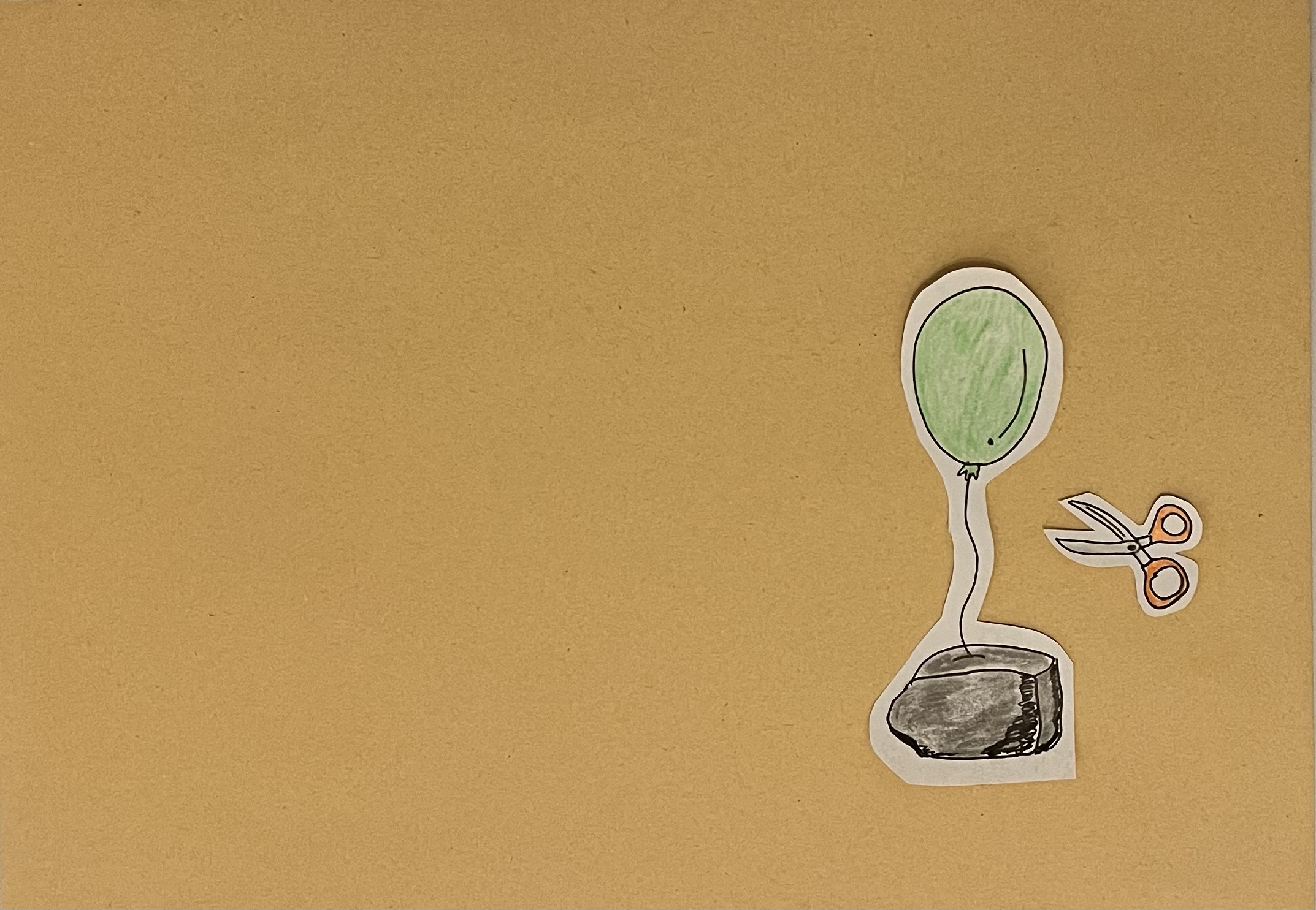 Ein Luftballon steckt in einem Stein fest. Daneben liegt eine Schere.